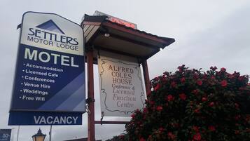 Placa do Settlers Motor Lodge com comodidades incluindo hospedagem, café licenciado, conferências, aluguel de espaço, casamentos e wifi gratuito.