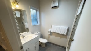 A bathroom with a white sink, toilet, and a towel rack. - Settlers Motor Lodge (Lower Hutt)