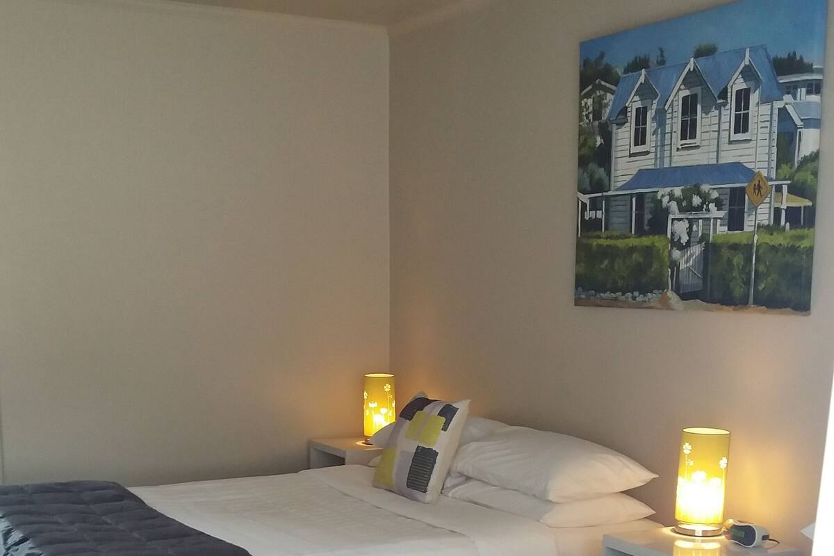 Ein Hotelzimmer mit zwei Betten, einem Nachttisch mit Lampe, einem Bild an der Wand und einem Teppichboden.