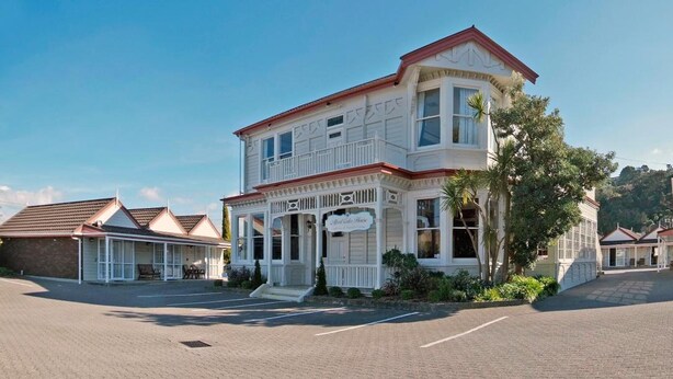 A two-story building with a bay window, a porch, and a sign that reads "The House." - Settlers Motor Lodge (Lower Hutt)