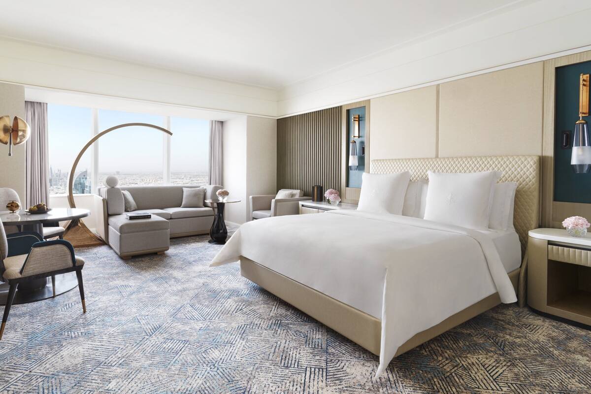 Habitación de hotel con una cama grande, un escritorio con una silla, un sofá y vistas a la ciudad.