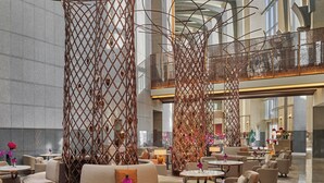 Un vestíbulo espacioso con techos altos, muebles modernos y separadores decorativos de metal.