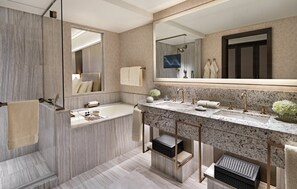 A modern bathroom with a large mirror, two sinks, a bathtub, and a shower.