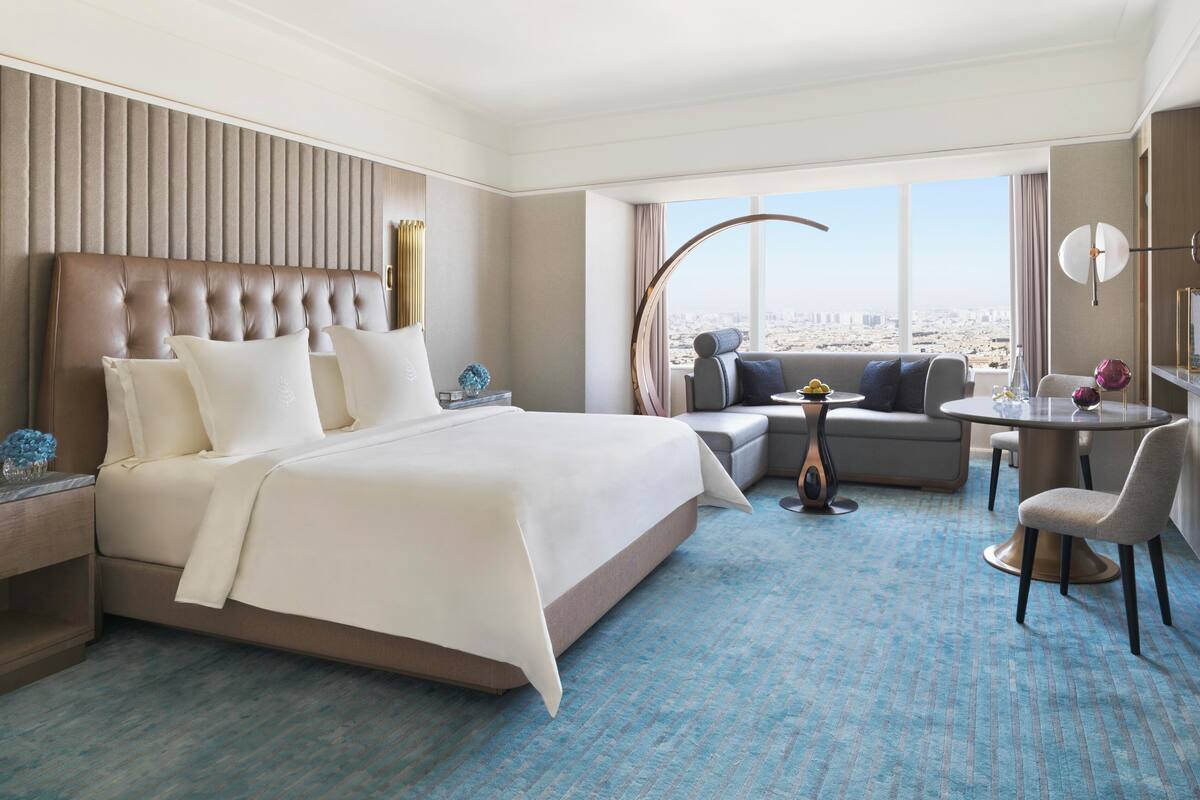 Una habitación de hotel con una cama grande, un sofá, una mesita y vistas a la ciudad.