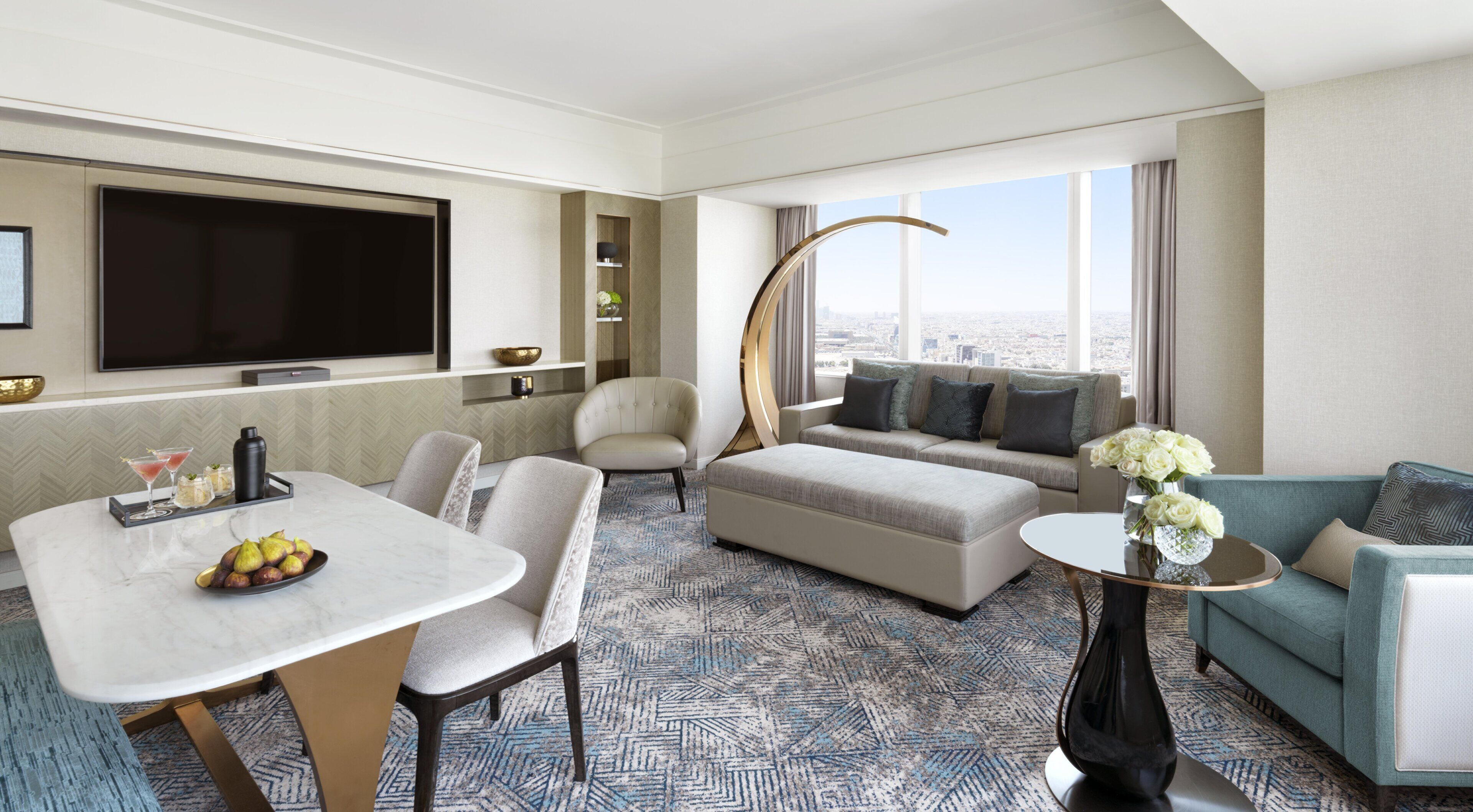 Una habitación de hotel moderna con zona de comedor, sofá y un amplio ventanal con vistas a la ciudad.