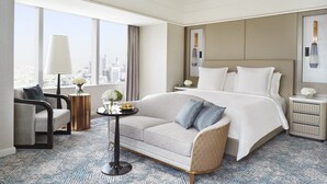 Habitación de hotel con una cama grande, un sofá, una mesita con flores, una l ámpara y vistas a la ciudad.