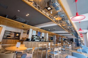 A modern cafe with a bar area, seating, and a variety of lighting fixtures.
