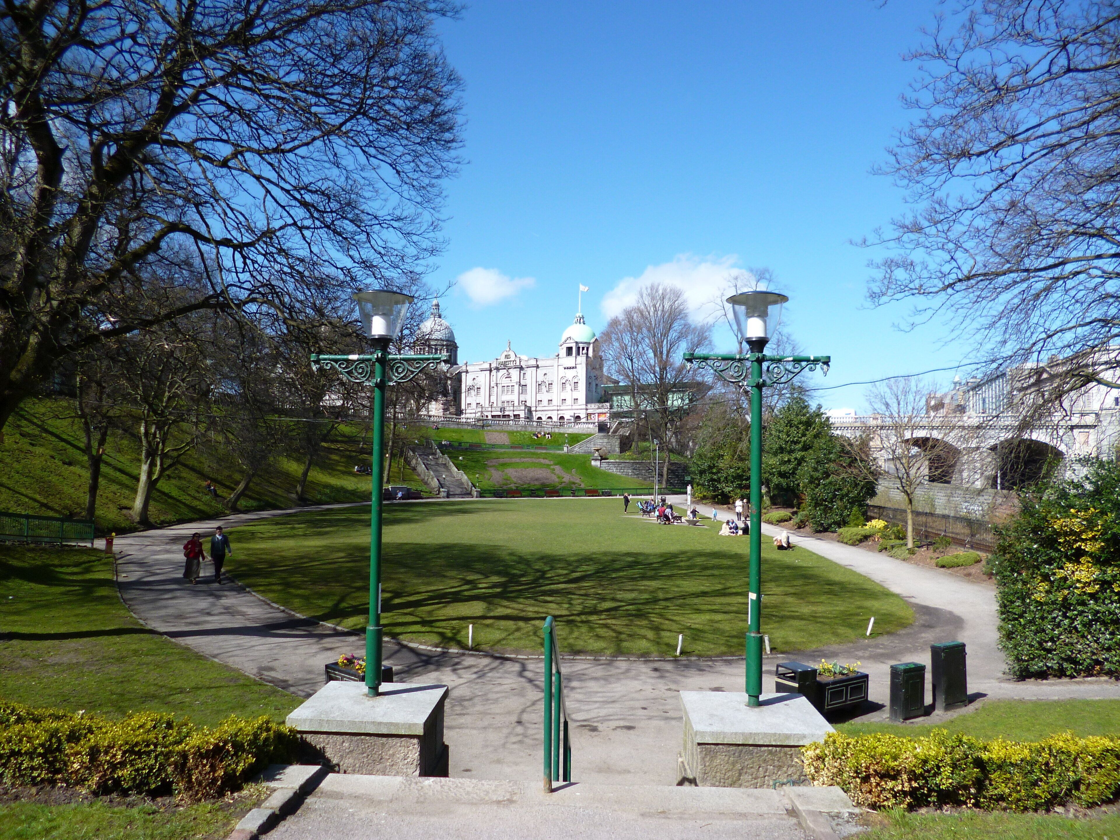 A park with a pathway leading to a building with domed architecture.