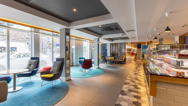 A modern interior with seating areas, a food display, and large windows. - Holiday Inn Express Aberdeen City Centre by IHG (Aberdeen)