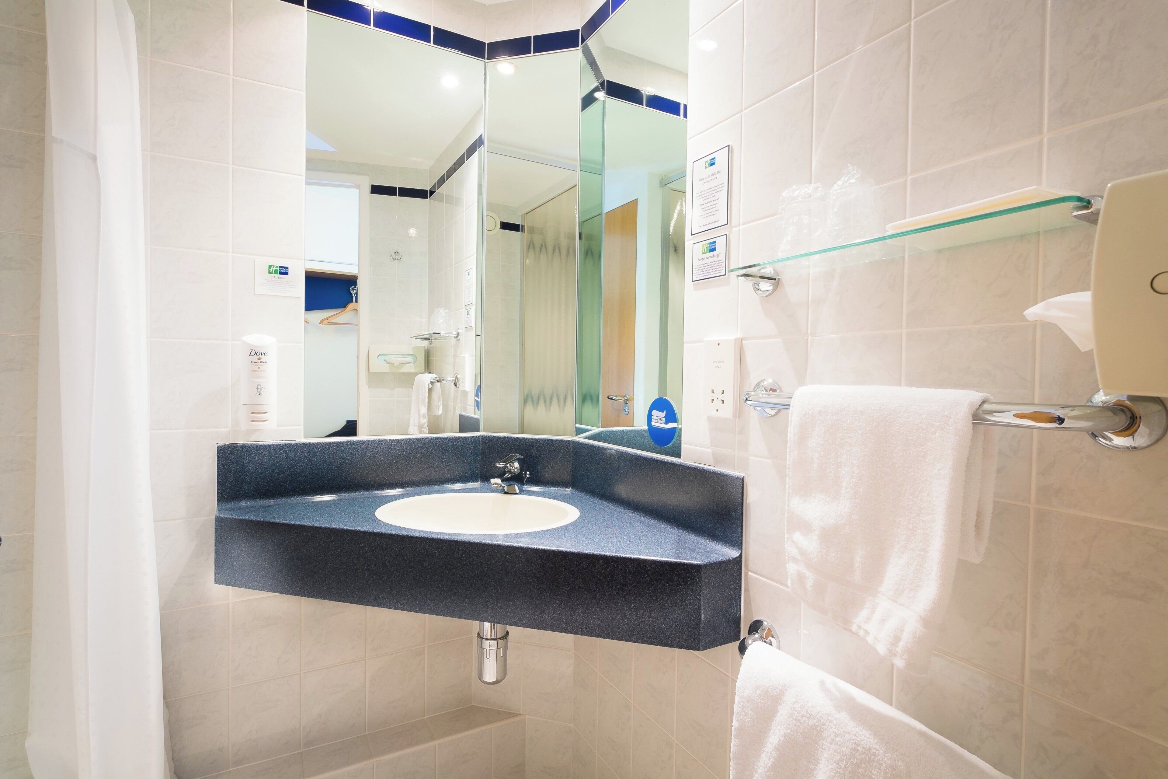 A bathroom with a sink, mirror, towel rack, and a glass shower enclosure.