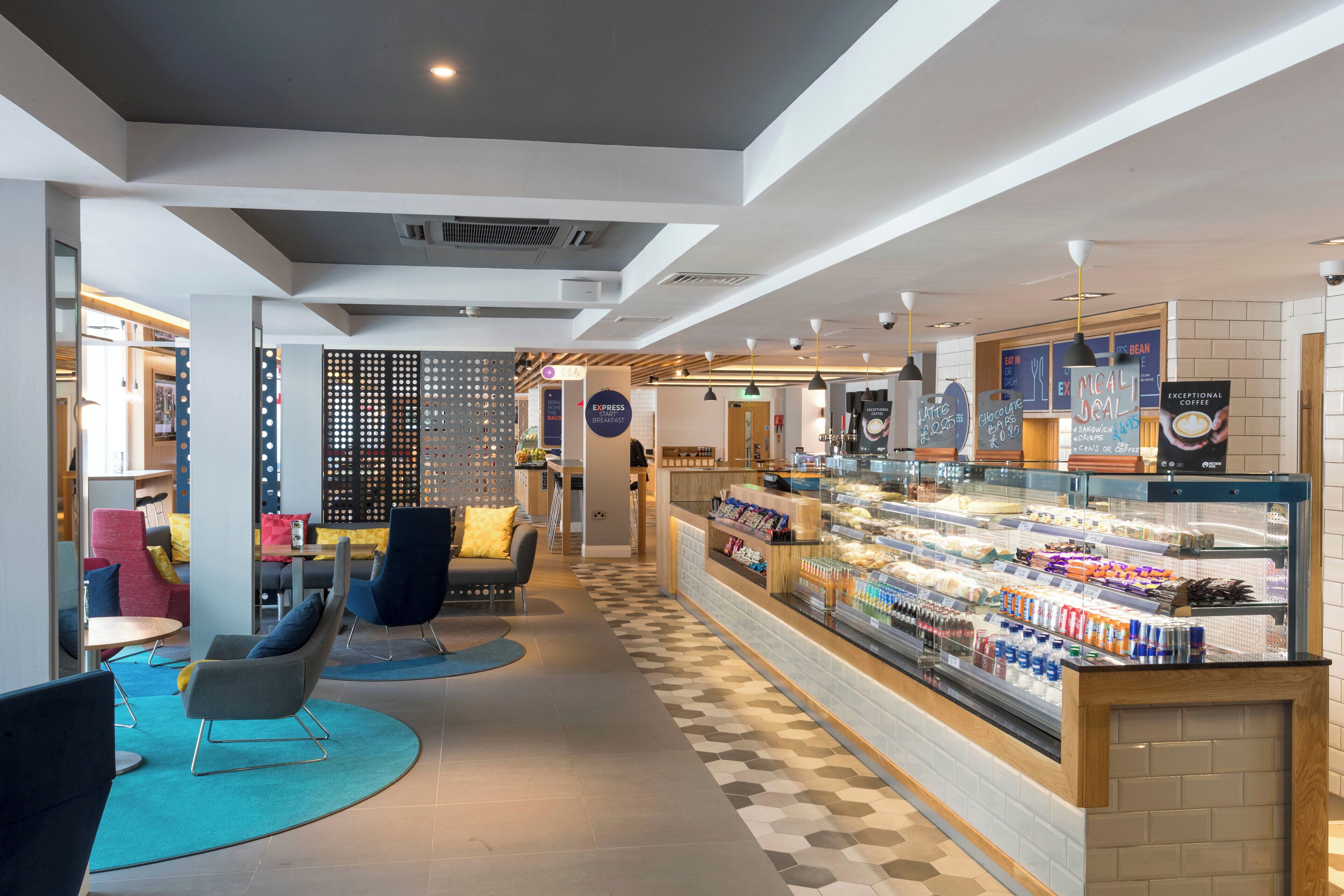 Een modern café met zitplaatsen, een vitrine met eten en een bord met de tekst ontbijt.