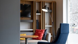 A modern living room with a sofa, a coffee table, a TV mounted on the wall, and a floor lamp. - Holiday Inn Express Aberdeen City Centre by IHG (Aberdeen)
