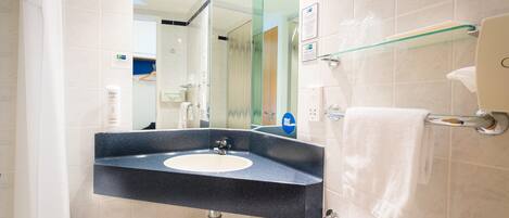 Un baño moderno con lavamanos de granito, cabina de ducha de vidrio y un perchero para toallas.