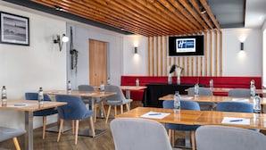 A modern hotel conference room with wooden tables, blue chairs, and a red sofa. - Holiday Inn Express Aberdeen City Centre by IHG (Aberdeen)