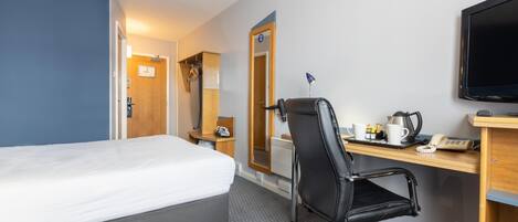 A hotel room with a bed, a desk with a chair, a television, and a mirror.