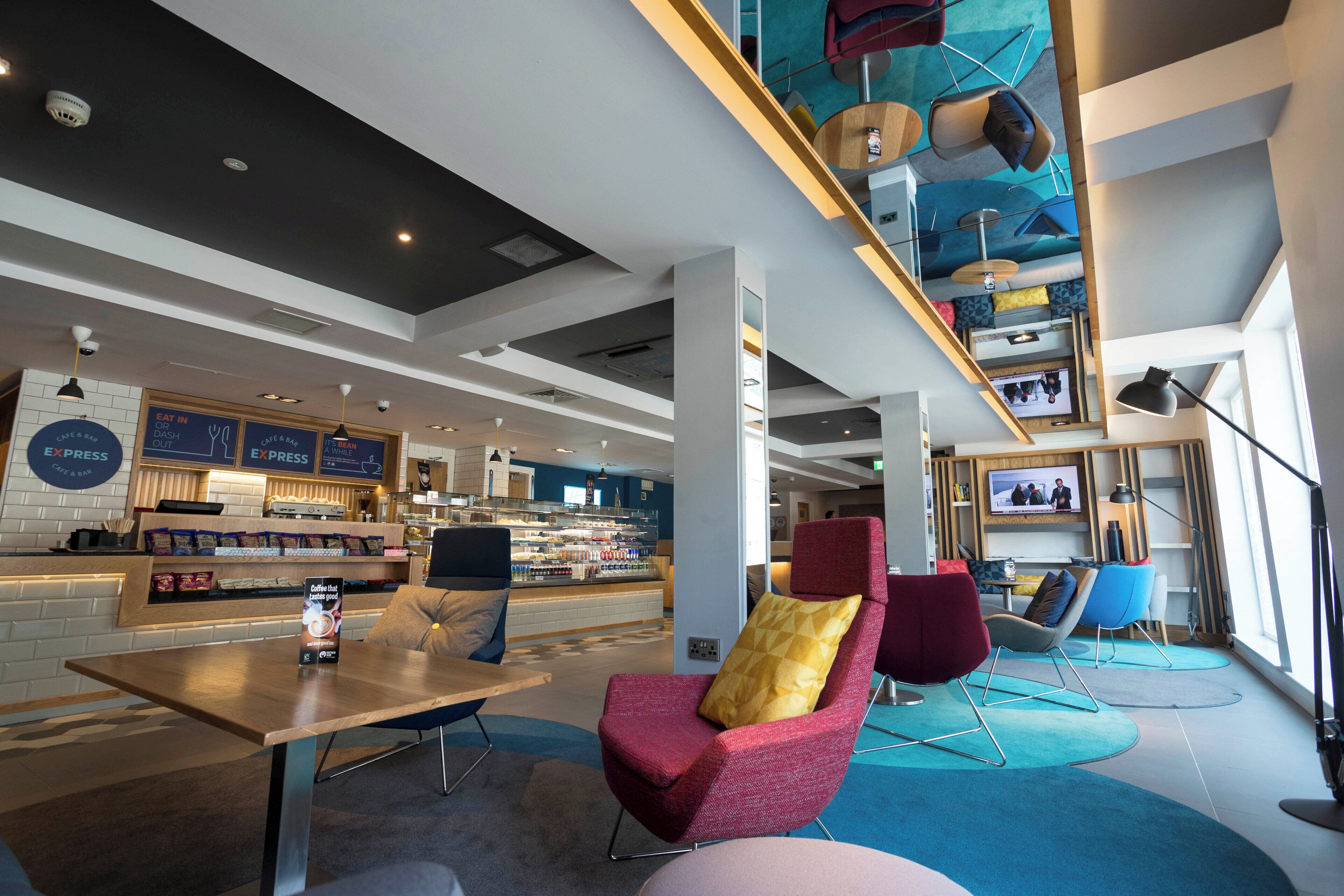 A modern cafe with seating, a coffee bar, and a television screen.
