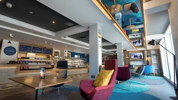 A modern cafe with seating, a coffee bar, and a television screen.