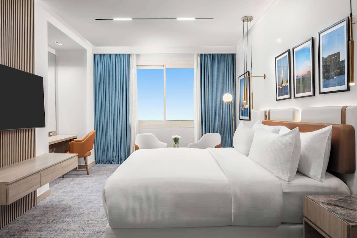 Una habitación de hotel moderna con una cama grande, un escritorio y un televisor.