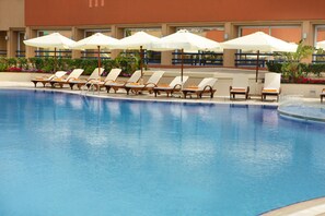 A pool area with lounge chairs and umbrellas.