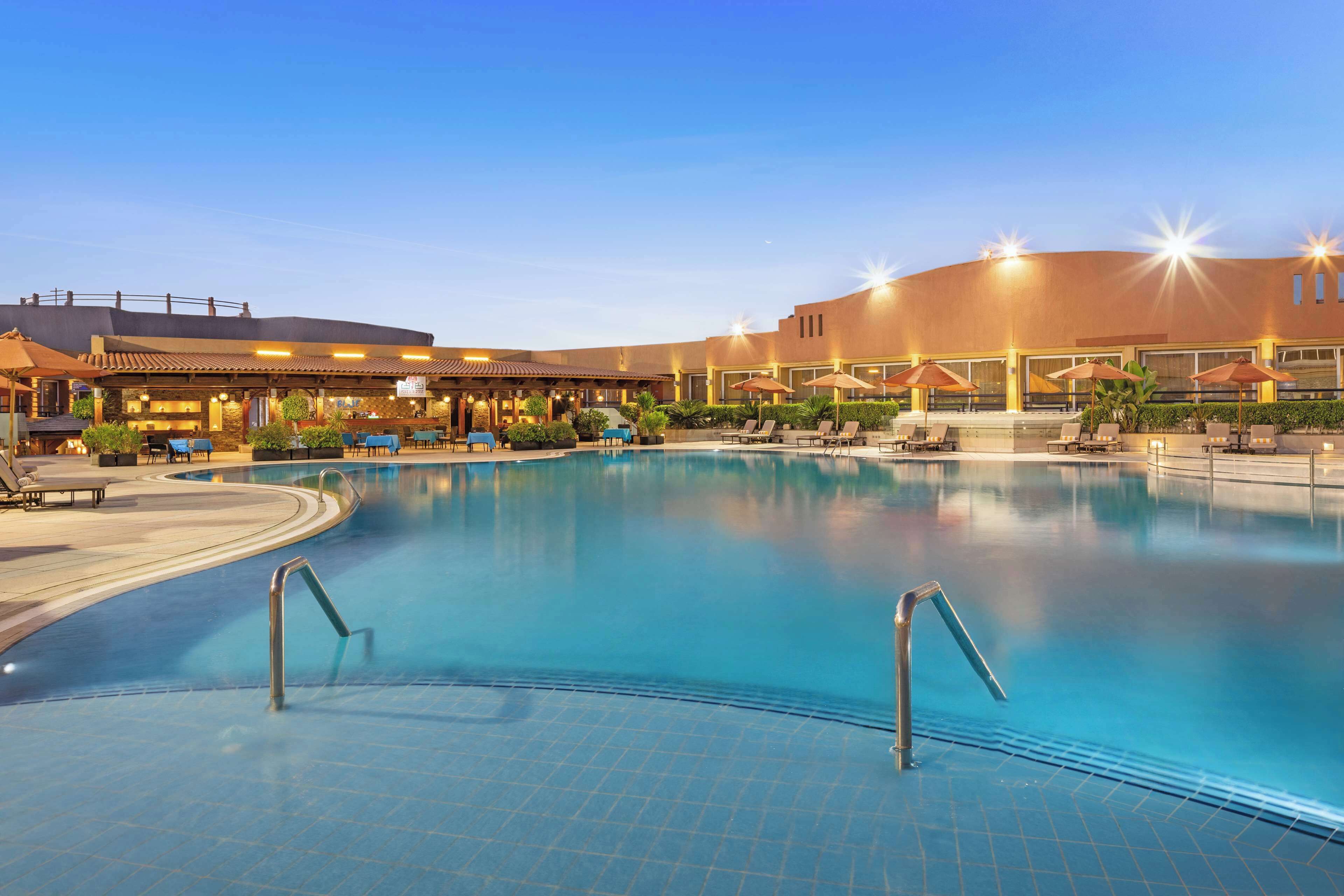 Una amplia piscina interior con zonas de descanso y un restaurante.