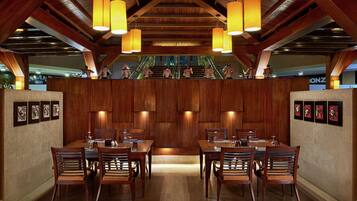 Un restaurante con paredes y techo de madera, varias mesas y sillas, y lámparas colgantes.