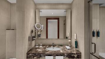 Un baño moderno con lavamanos de mármol, un espejo grande y cabina de ducha de vidrio.
