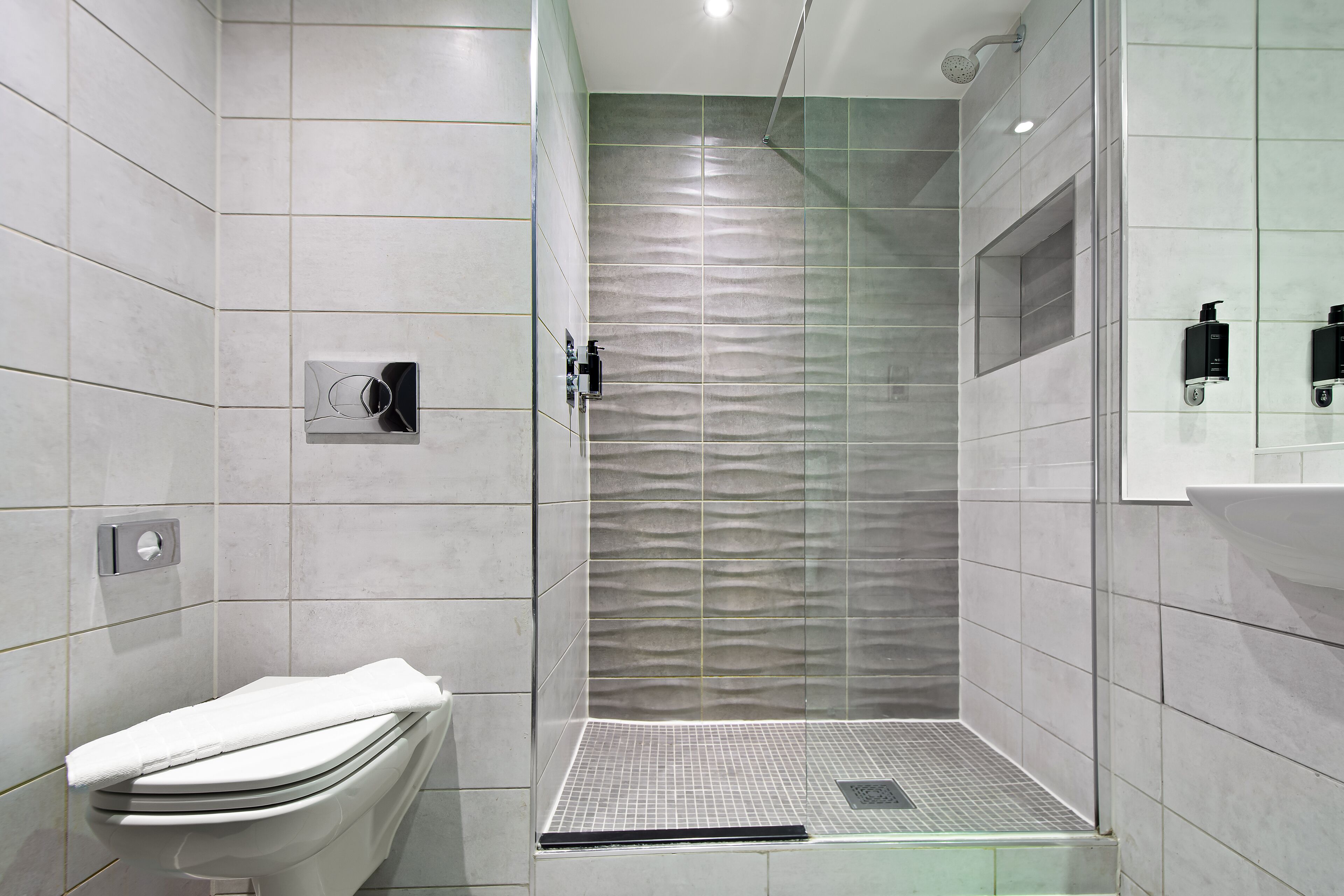 Une salle de bain moderne équipée d’une douche, de toilettes et d’un lavabo.