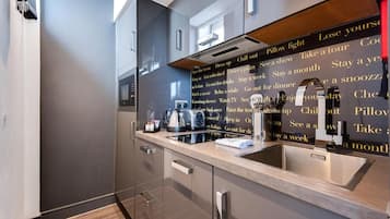 A modern kitchen with a built-in microwave, kettle, and coffee maker.