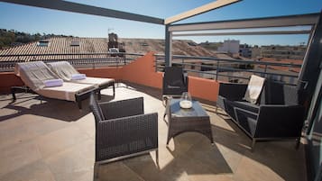 Una terraza en la azotea con sillones, una mesa y vistas a la ciudad.