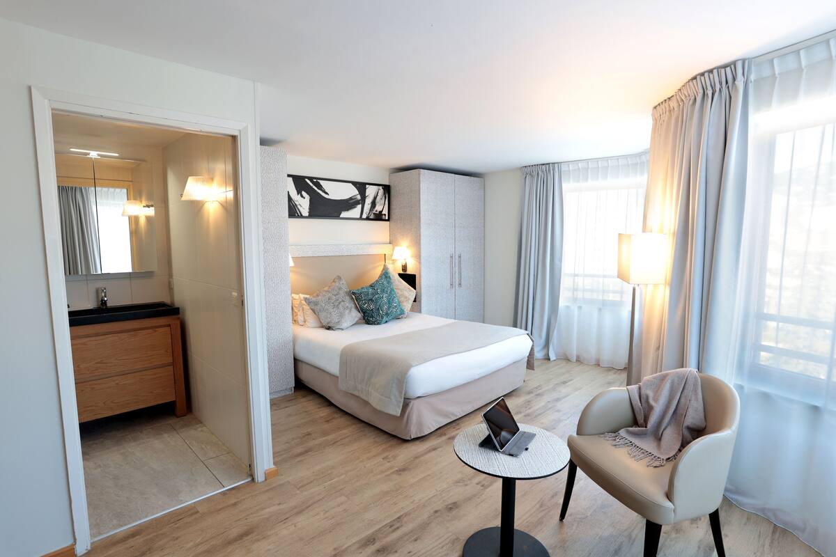 Une chambre d’hôtel moderne équipée d’un lit, d’un bureau, d’une chaise, d’une armoire et d’une salle de bain.