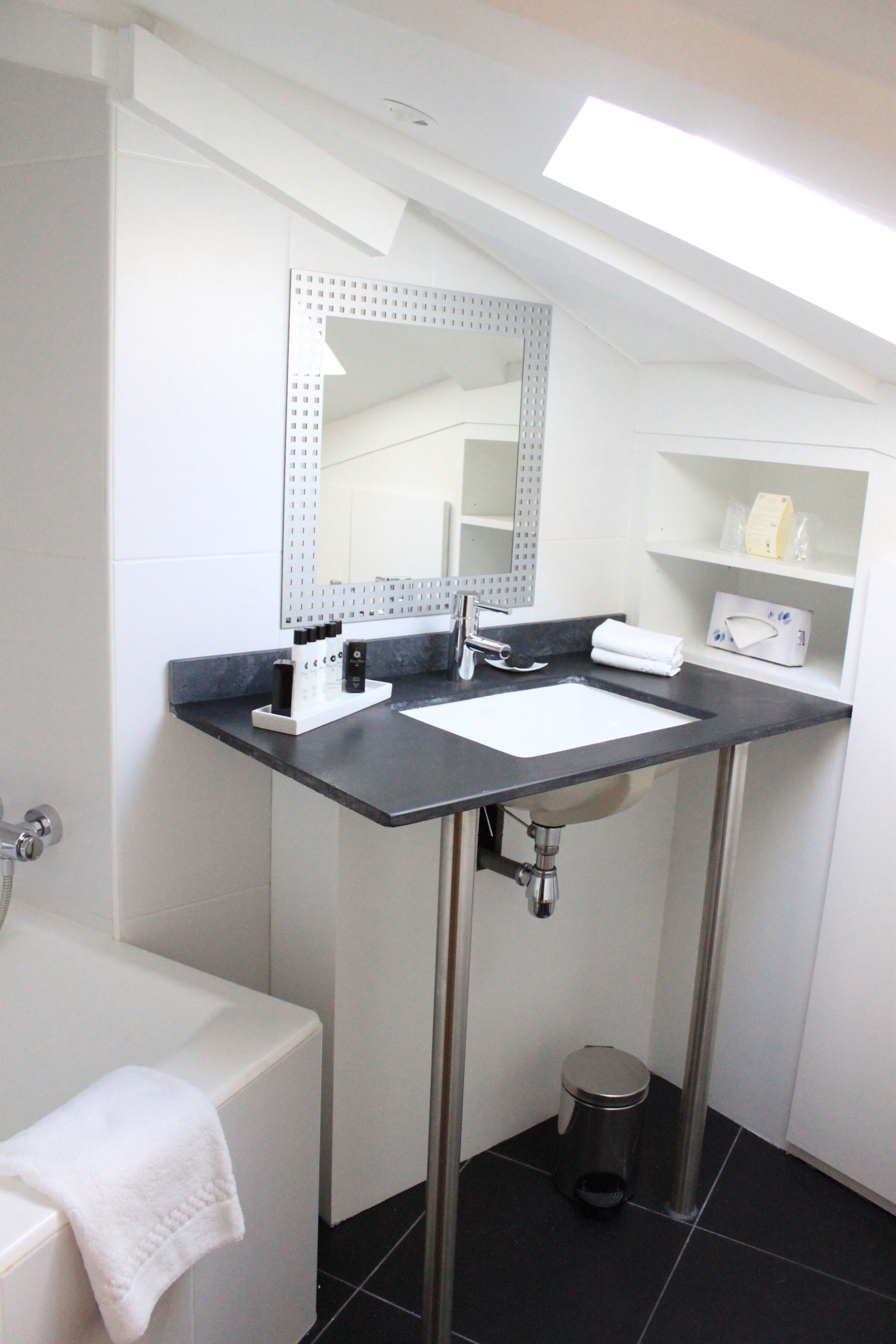 A modern bathroom with a white sink, a mirror, and a bathtub.