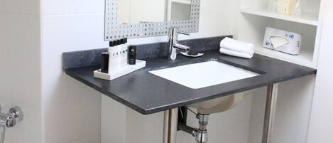 A modern bathroom with a white sink, a mirror, and a bathtub.