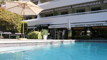 Ein Hotel mit Poolbereich, Sitzgelegenheiten im Freien und einer Bar.