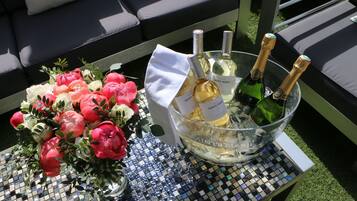 Une table recouverte d’une nappe à motifs de mosaïque, un saladier en verre contenant des bouteilles de champagne et un bouquet de fleurs.