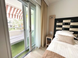 Een hotelkamer met een bed, nachtkastje, spiegel en een schuifdeur naar een balkon.