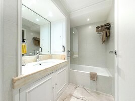 A modern bathroom with a large mirror, a sink, a shower, and a bathtub.