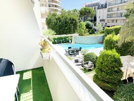 A balcony with a pool, outdoor furniture, and lush greenery.