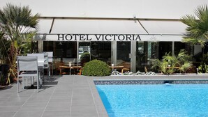 Um hotel chamado HOTEL VICTORIA com piscina e área de estar ao ar livre.