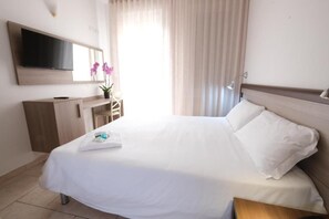 A hotel room with a bed, a TV mounted on the wall, a desk, and a window with curtains. - Hotel Nuovo Metrò (Milan)