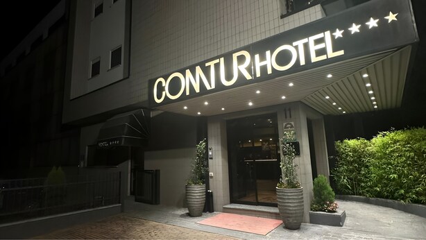 The exterior of a hotel with a prominent illuminated sign reading "CONJURHOTEL". - Hotel Comtur (Binasco)