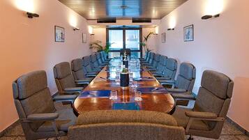 A conference room with a long table, multiple chairs, and a large window in the background.