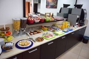 Ein reichhaltiges Buffet mit verschiedenen Speisen und Getränken, darunter Obst, Gebäck und Beilagen.