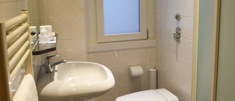 A bathroom with a sink, toilet, and a window.