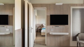Ett modernt hotellrum med en TV som är monterad på väggen, en soffa och en säng i bakgrunden.