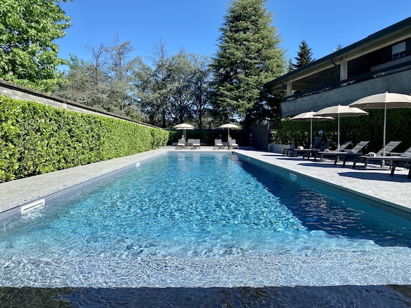 Una piscina al aire libre de temporada, sombrillas