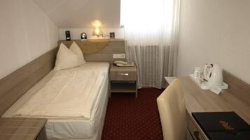 Une chambre d’hôtel comprenant un lit, une table de chevet, une lampe et un bureau avec une chaise.