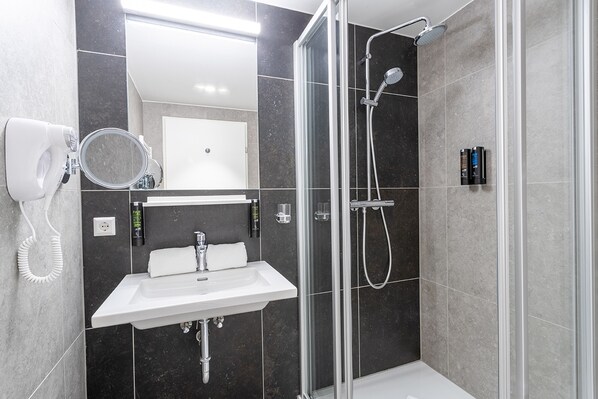A modern bathroom with a glass-enclosed shower, a sink, and a mirror.