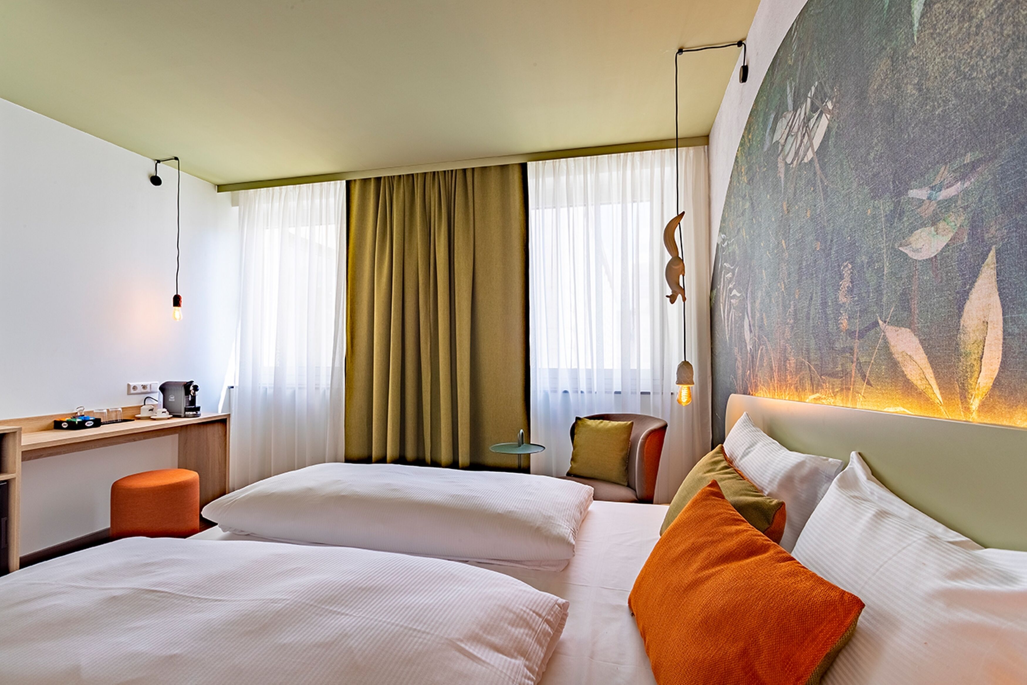 Een hotelkamer met twee bedden, een bureau, een stoel en een groot schilderij aan de muur.