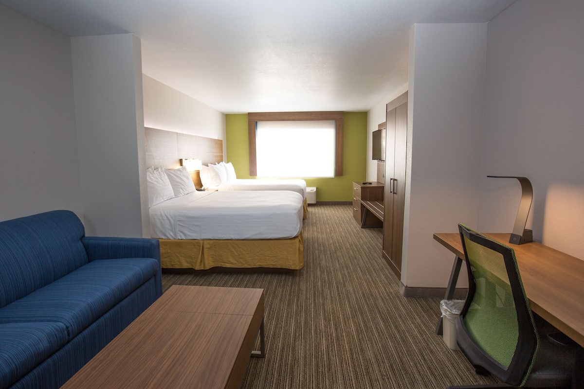 A hotel room with a bed, a desk, a chair, a sofa, and a TV.