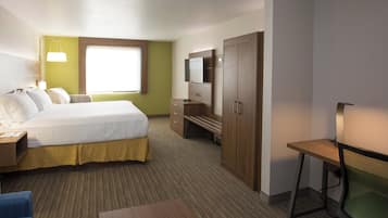 A hotel room with a bed, a desk, a TV, and a window.
